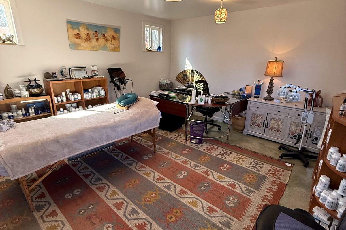 Treatment room at our Santa Fe office — kilim rug, warm lamplight, and a well-stocked apothecary